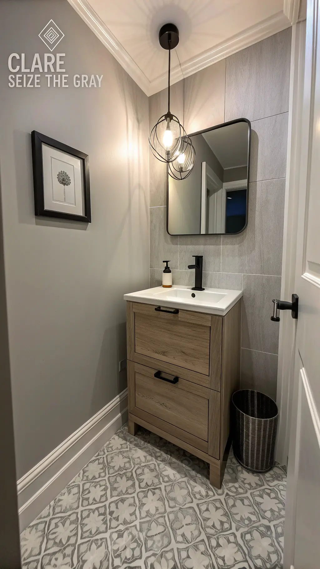 Compact powder room featuring modern pendant fixture, weathered oak floating vanity, geometric cement floor tiles and minimalist black-framed art with dusk lighting.